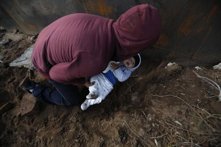 Migrants in Tijuana trickling over and under wall