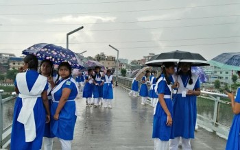 Students with umbrellas in a light rain on the overbridge in Hatirjheel, Dhaka on Tuesday