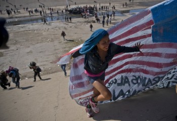 US agents fire tear gas as some migrants try to breach fence